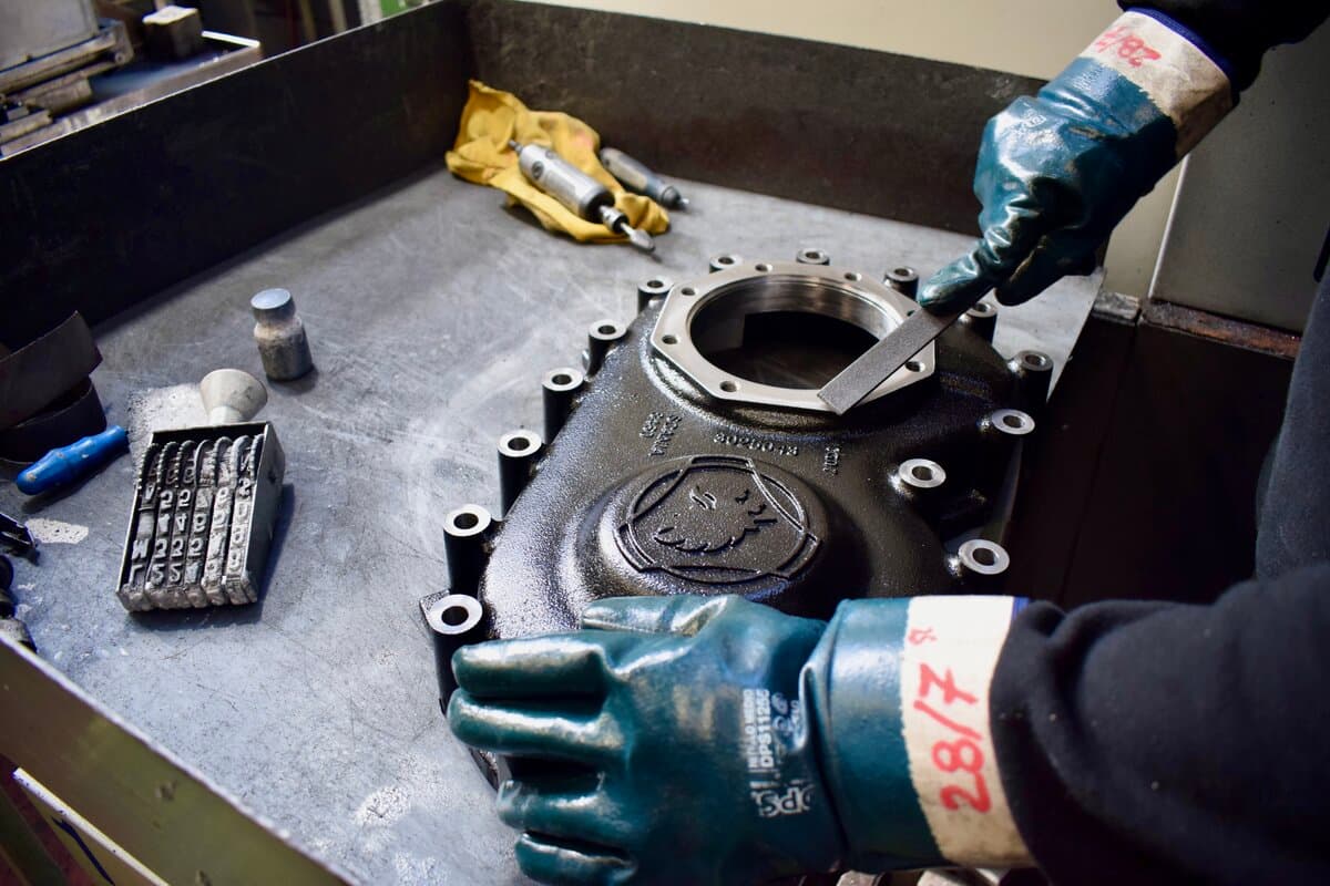 Worker lifting a machined part with a crane hook at KAELE SRL